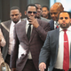 R. Kelly covers his mouth as he speaks to members of his entourage as he arrives at the Leighton Criminal Courts Building for a hearing on June 26, 2019 in Chicago, Ill.